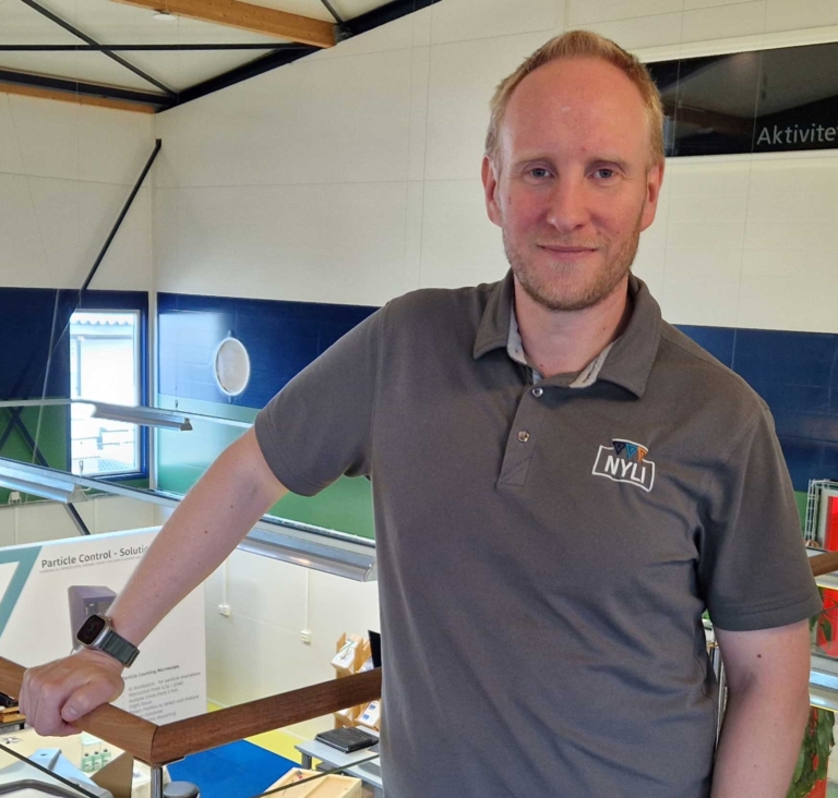 Andreas Thorn står lutad mot ett räcke och blickar ut över NYLI:s labbmiljö med teknikstationer och utbildningsmaterial. Han pratar om framtidens proffs i industrin och hur skolor och företag jobbar tillsammans.