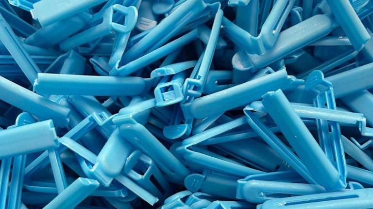 Blå plastklämmor i en hög används för montering i distanssystem. Klimatsmart material som får nytt liv.