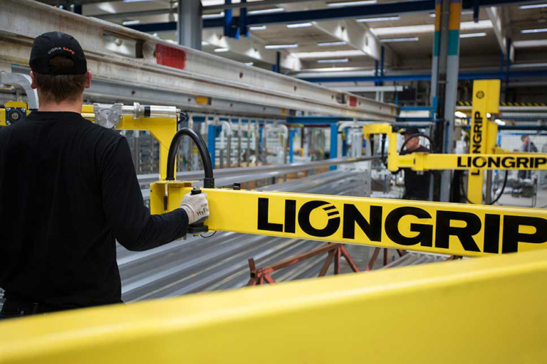 Operatör arbetar med ett gult innovativt LionGrip lyfthjälpmedel i en modern industrilokal. Foto: Mattias Holter