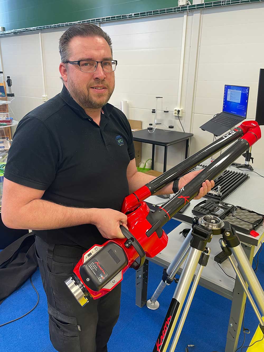 En medarbetare på NYLI håller i ett avancerat mätinstrument med kolfiberdelar och digital display.