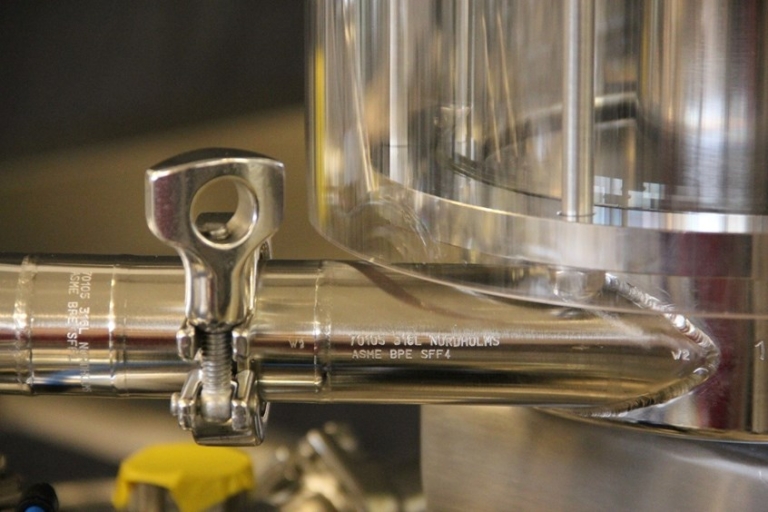 Närbild på rostfritt ASME BPE-märkt processrör från Nordholms med hygienisk klämkoppling. Effektiv produktion.