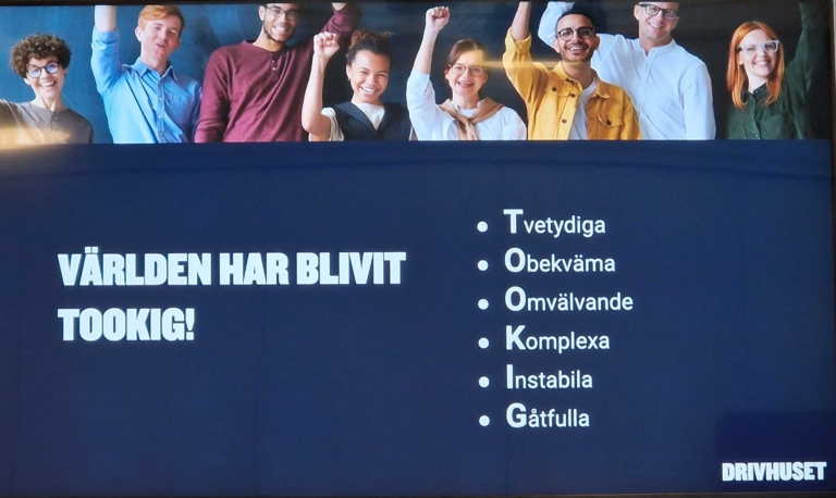 Bildspel med texten ”Världen har blivit tookig!” samt en akronym där varje bokstav står för ett ord: Tvety­diga, Obekväma, Omvälvande, Komplexa, Instabila och Gåtfulla. Överst syns en grupp människor som jublar.
