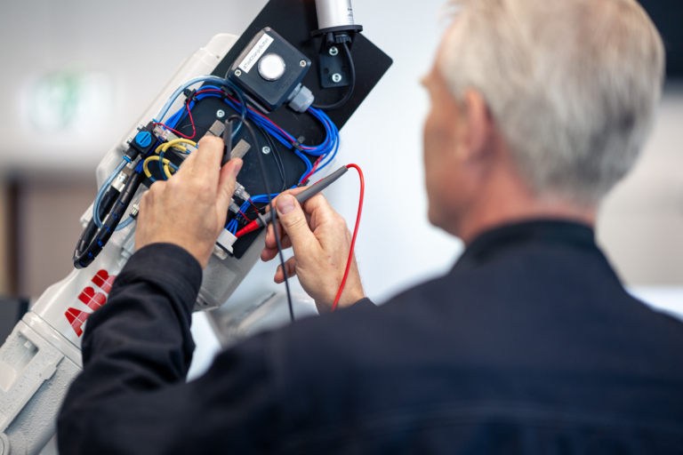 Närbild på händer som arbetar med digitalisering och teknisk utrustning under ett industriprojekt. Automation och produktion.