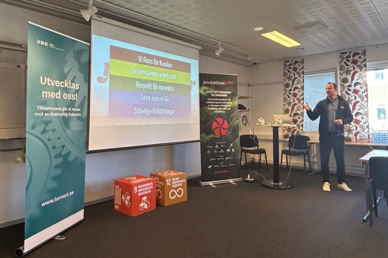 Andreas Unger från Jätten Cater presenterar företags arbete med Produktionslyftet under en fokusgrupp. En presentation med företagets värdeord projiceras på skärmen. man är en industriell förebild.