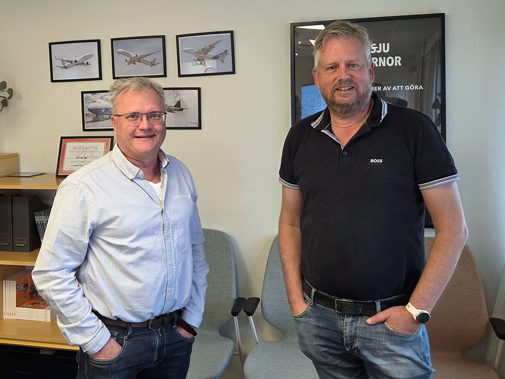 Kjell Johansson från Smart Storing och Tony Drechsel från Fortiva på kontor, stående framför vägg med flygbilder.