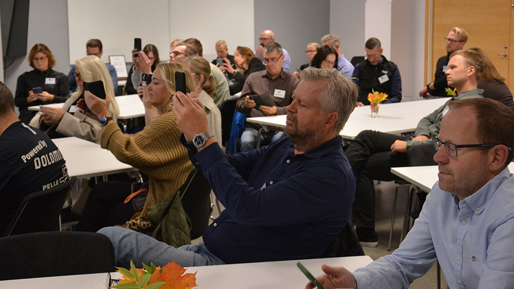 Deltagare fotograferar en presentation under insiktsseminariet.