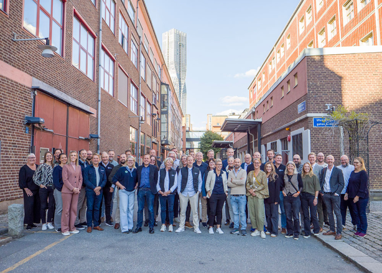 Gruppfoto med cirka 50 deltagare från Industry In West samlade mellan två tegelbyggnader i Göteborg, med höghuset Karlatornet i bakgrunden.