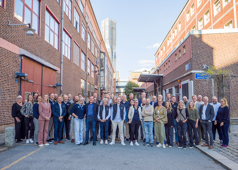 Gruppfoto med cirka 50 deltagare från Industry In West samlade mellan två tegelbyggnader i Göteborg, med höghuset Karlatornet i bakgrunden.