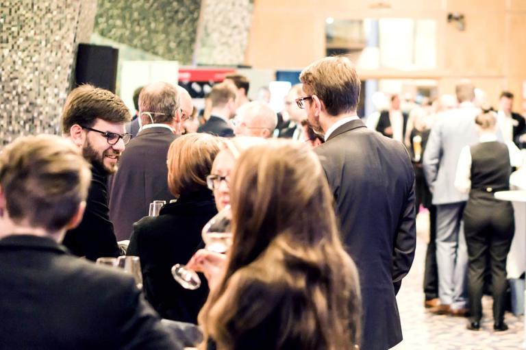 Deltagare nätverkar under en konferens med mingel och samtal i en ljus lokal.