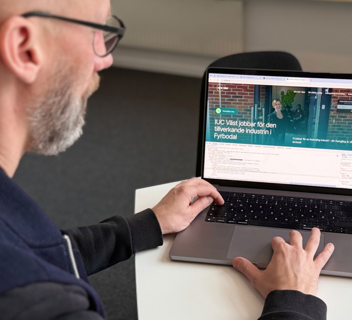 Person arbetar vid en laptop och granskar en webbsida i webbläsarens utvecklarverktyg. Webbplats tillgänglighet.