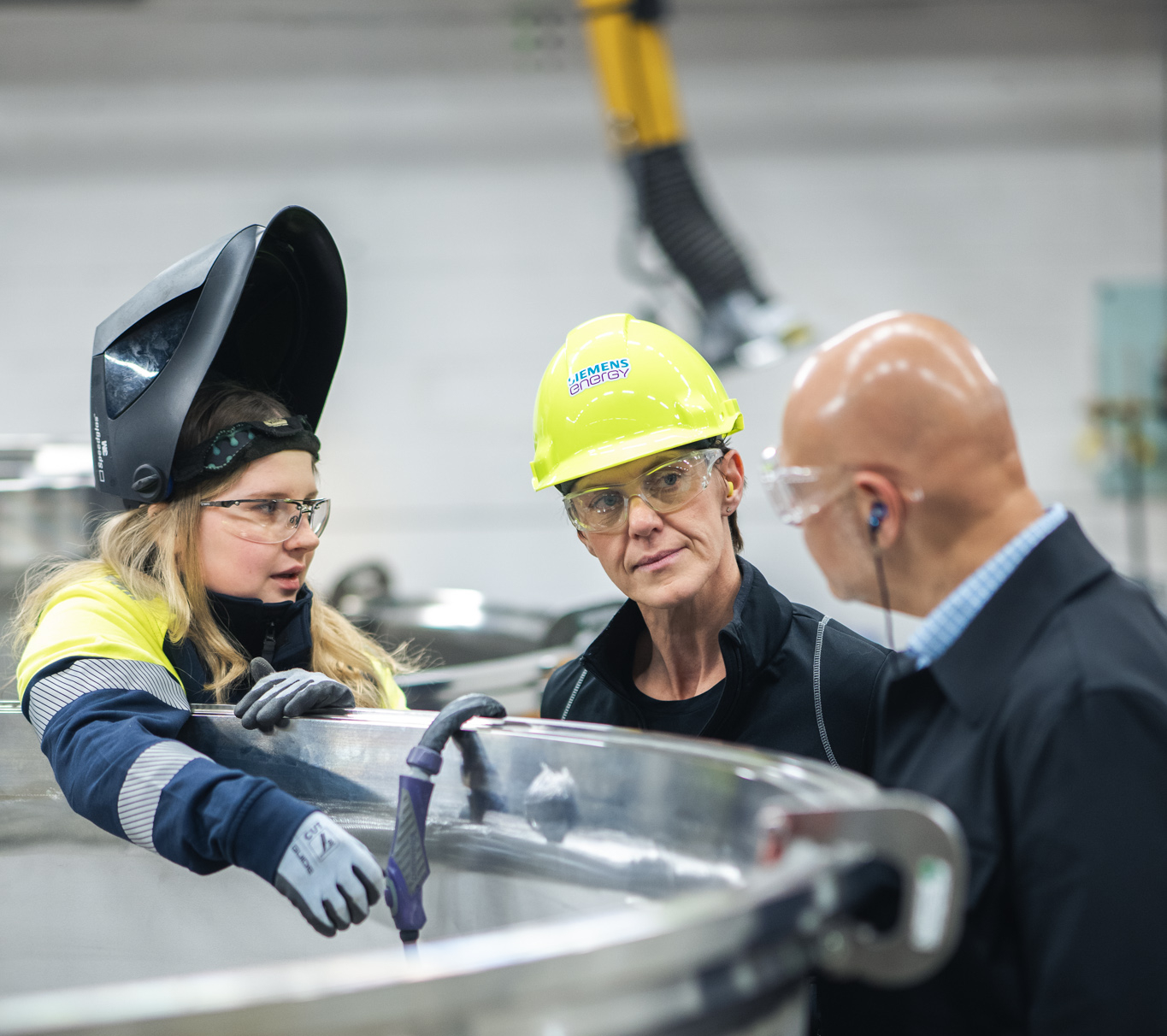 Tre personer samtalar vid industriell utrustning i en produktionsmiljö inom ramen för projektet SVAN.