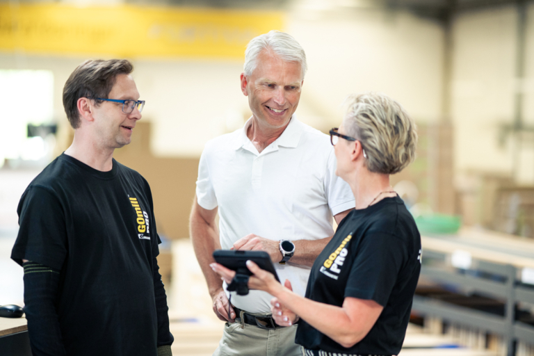 Håkan Hellström från IUC Väst i samtal med två medarbetare under ett företagsbesök i en industrimiljö.